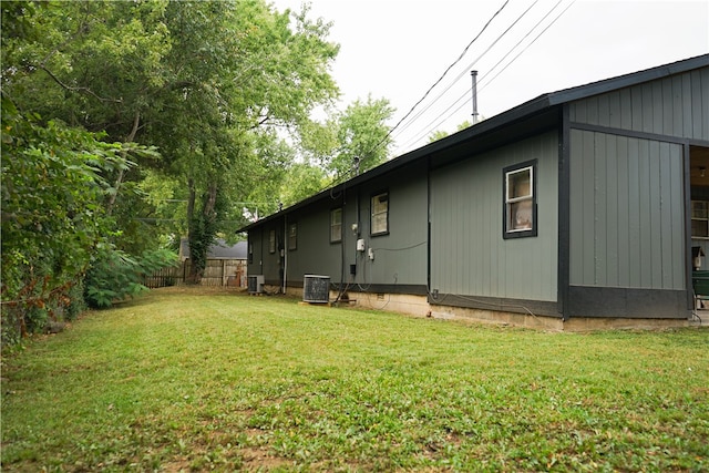 view of side of property featuring a lawn and central AC