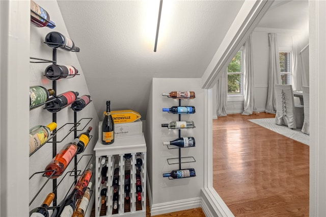 wine area with a textured ceiling and hardwood / wood-style flooring