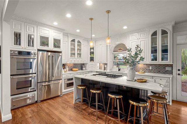 kitchen featuring light hardwood / wood-style flooring, appliances with stainless steel finishes, decorative backsplash, and a kitchen island