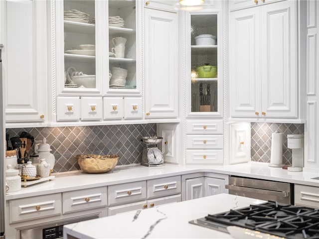 kitchen with stainless steel gas stovetop, decorative backsplash, and white cabinets