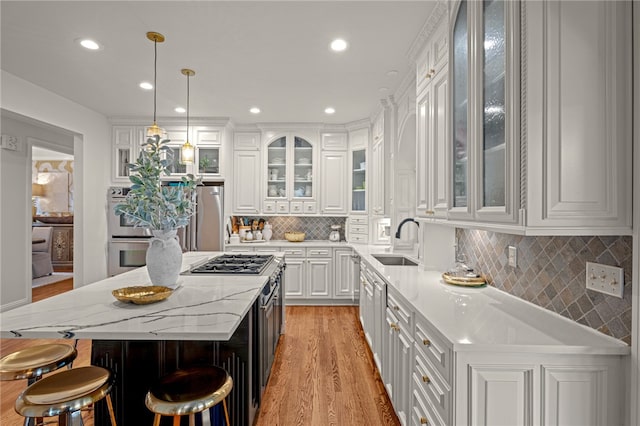 kitchen featuring white cabinets, sink, a kitchen island, decorative light fixtures, and light hardwood / wood-style flooring