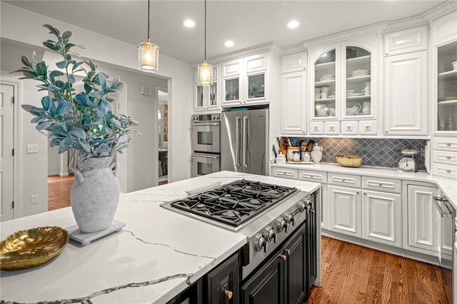 kitchen with white cabinetry, appliances with stainless steel finishes, hardwood / wood-style flooring, and decorative light fixtures