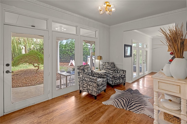 sitting room with french doors, ornamental molding, a chandelier, and hardwood / wood-style floors