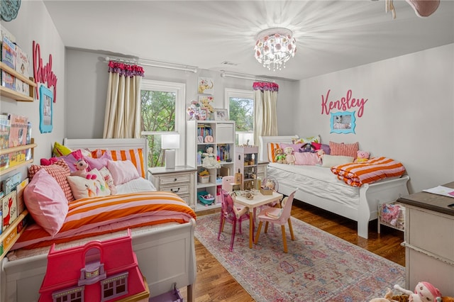 bedroom with a notable chandelier and dark wood-type flooring