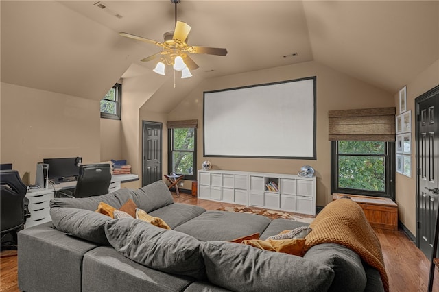 home theater room with light hardwood / wood-style floors, vaulted ceiling, and ceiling fan