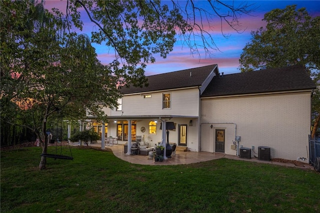 16 W Wimbledon Way, Rogers, AR 72758 - back of house at dusk with a lawn, central air condition unit, a patio area, and brick siding