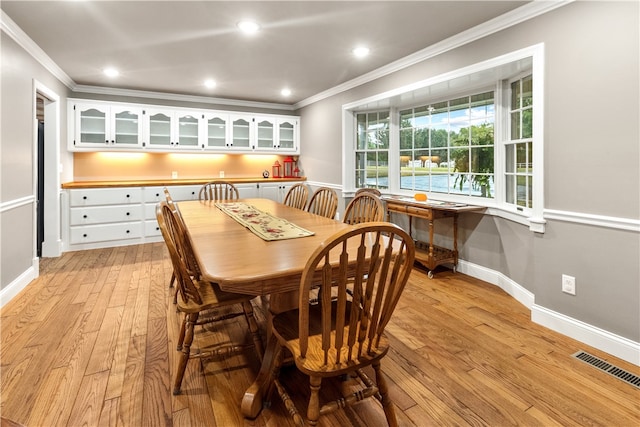 dining space with light wood-type flooring and ornamental molding