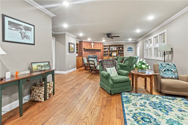 living room featuring ceiling fan, light wood-type flooring, a fireplace, and ornamental molding