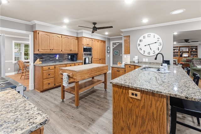 kitchen with ceiling fan, sink, kitchen peninsula, crown molding, and light wood-type flooring