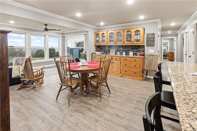 dining room with crown molding, ceiling fan, and light wood-type flooring