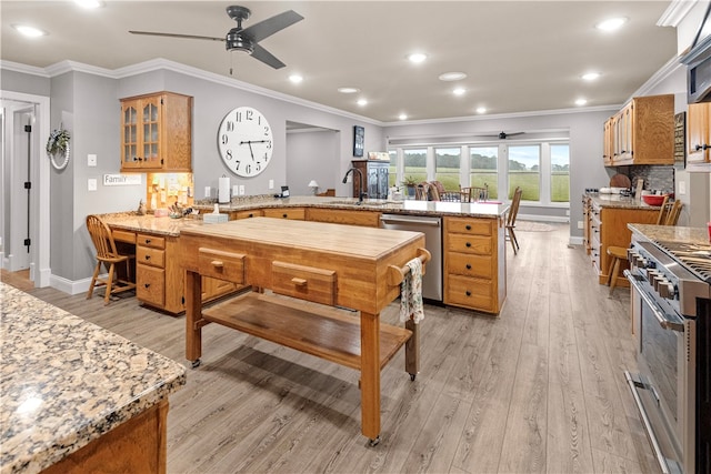 kitchen featuring crown molding, ceiling fan, appliances with stainless steel finishes, light hardwood / wood-style floors, and kitchen peninsula