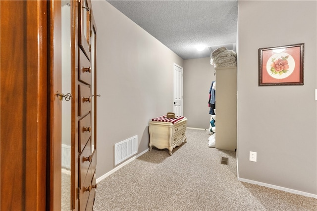 corridor featuring light carpet and a textured ceiling