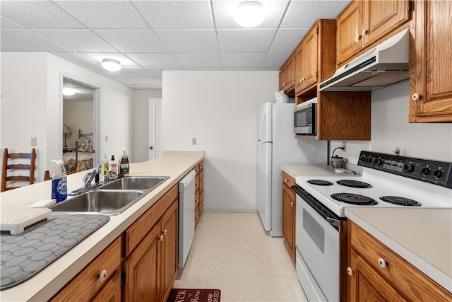 kitchen with a paneled ceiling, white appliances, and sink