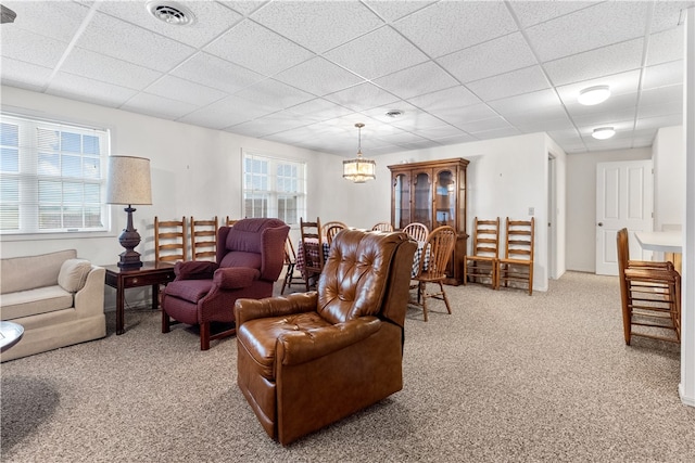 living room with a drop ceiling, light colored carpet, and a wealth of natural light