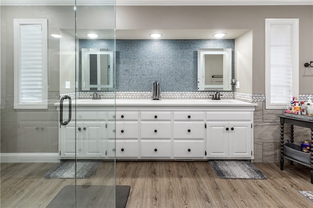 bathroom featuring vanity, hardwood / wood-style flooring, ornamental molding, tile walls, and walk in shower