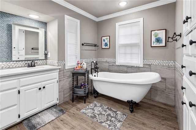 bathroom featuring vanity, crown molding, hardwood / wood-style flooring, tile walls, and a tub