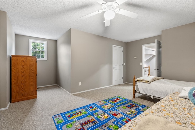 carpeted bedroom featuring ceiling fan and a textured ceiling