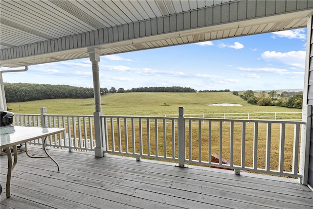 wooden terrace with a rural view and a lawn