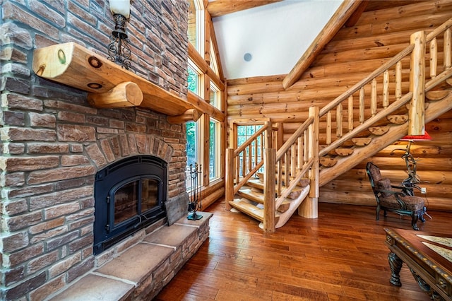 living room featuring a fireplace, log walls, hardwood / wood-style floors, and high vaulted ceiling