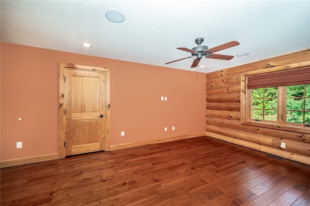 empty room featuring a textured ceiling, wooden walls, dark hardwood / wood-style floors, and ceiling fan