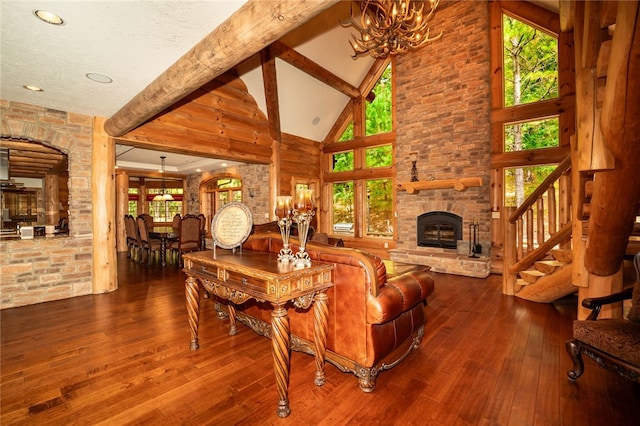 living room featuring a healthy amount of sunlight, a fireplace, high vaulted ceiling, and a notable chandelier