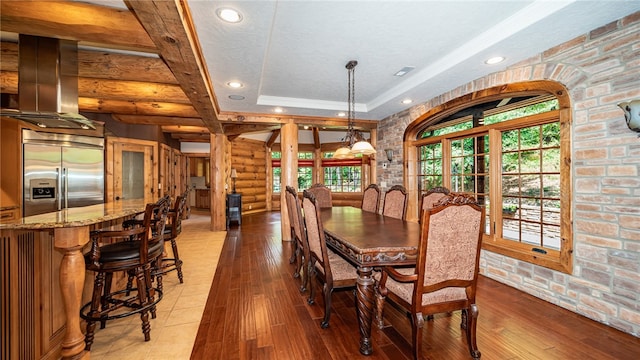 dining area featuring light hardwood / wood-style flooring, a raised ceiling, and beamed ceiling