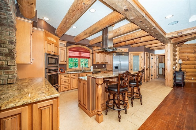 kitchen with stainless steel appliances, rustic walls, beam ceiling, and a kitchen island