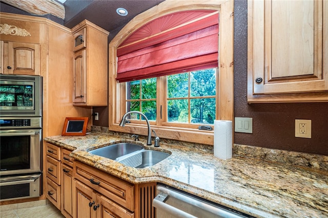 kitchen featuring light stone counters, appliances with stainless steel finishes, light tile patterned floors, and sink