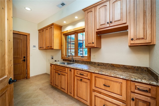 kitchen featuring dark stone counters, light tile patterned flooring, and sink