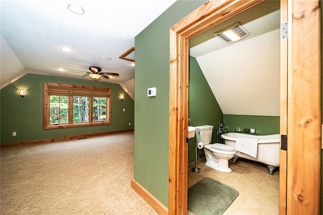 bathroom with ceiling fan, vaulted ceiling, a bathing tub, and toilet