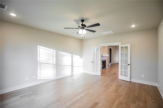 empty room featuring ceiling fan, light wood-type flooring, and french doors