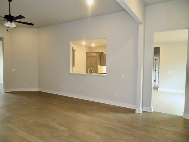 spare room featuring wood finished floors, baseboards, and ceiling fan