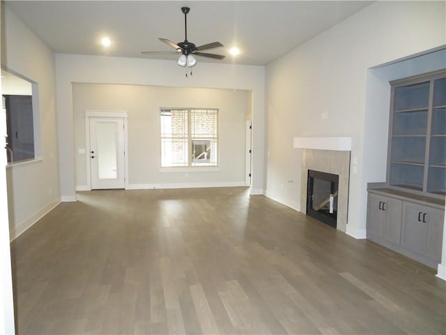 unfurnished living room featuring a ceiling fan, wood finished floors, a fireplace, and baseboards