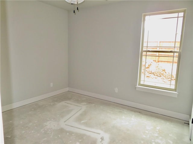 unfurnished room featuring baseboards and unfinished concrete flooring