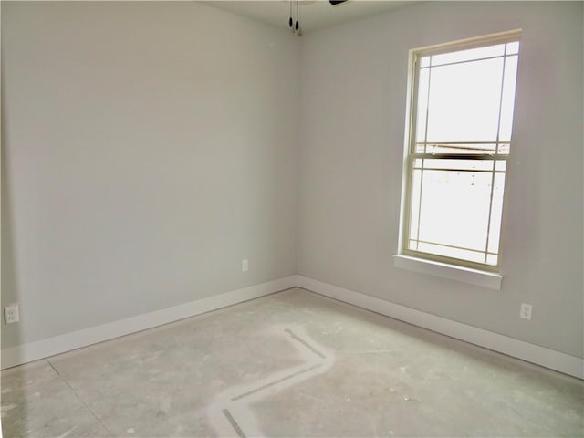 spare room featuring a healthy amount of sunlight, baseboards, and ceiling fan