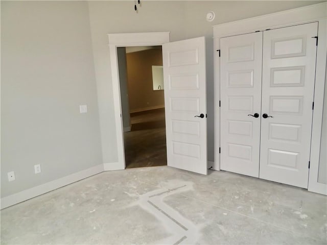 unfurnished bedroom with baseboards, a closet, and concrete flooring