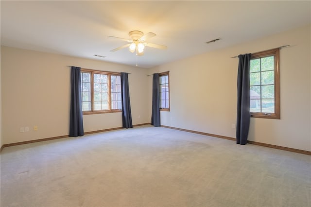 unfurnished room featuring ceiling fan, light carpet, and a wealth of natural light