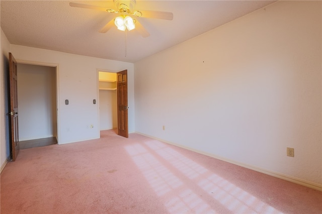 unfurnished bedroom featuring ceiling fan, light colored carpet, a closet, and a spacious closet