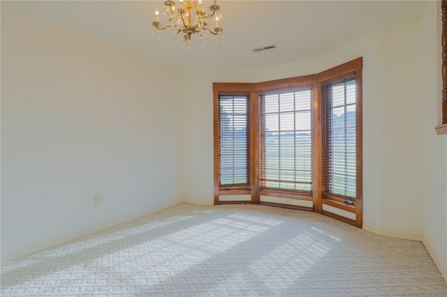 carpeted empty room featuring a chandelier