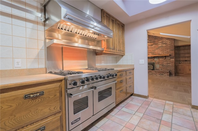 kitchen featuring decorative backsplash, range with two ovens, and brick wall