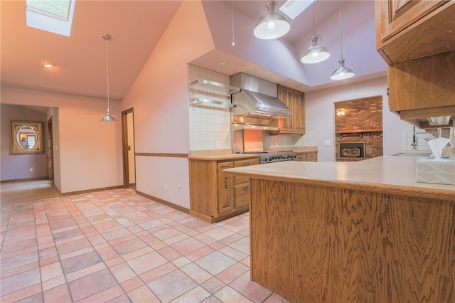 kitchen with decorative light fixtures, kitchen peninsula, wall chimney range hood, and decorative backsplash