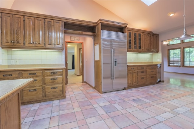 kitchen with hanging light fixtures, decorative backsplash, light tile patterned flooring, lofted ceiling with skylight, and high end fridge