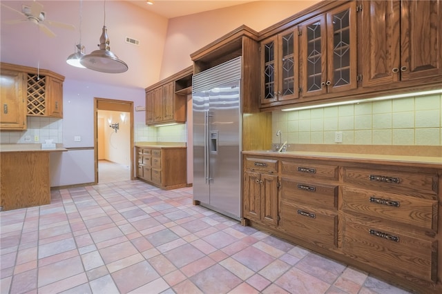 kitchen with hanging light fixtures, backsplash, lofted ceiling, ceiling fan, and stainless steel built in fridge