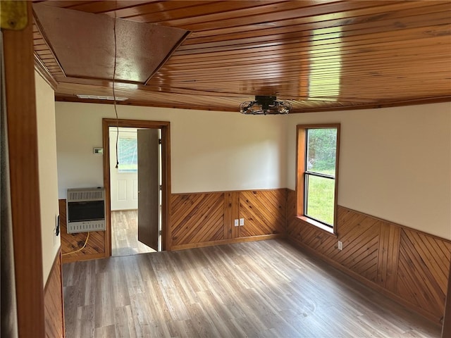 empty room featuring wood-type flooring, wood ceiling, wood walls, and heating unit