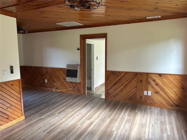 spare room featuring wooden ceiling, wood-type flooring, wood walls, and heating unit