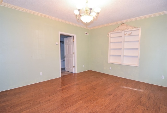 spare room featuring visible vents, crown molding, wood finished floors, and an inviting chandelier