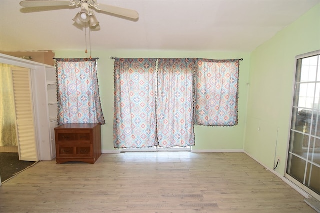 unfurnished room featuring a ceiling fan, baseboards, vaulted ceiling, and wood finished floors