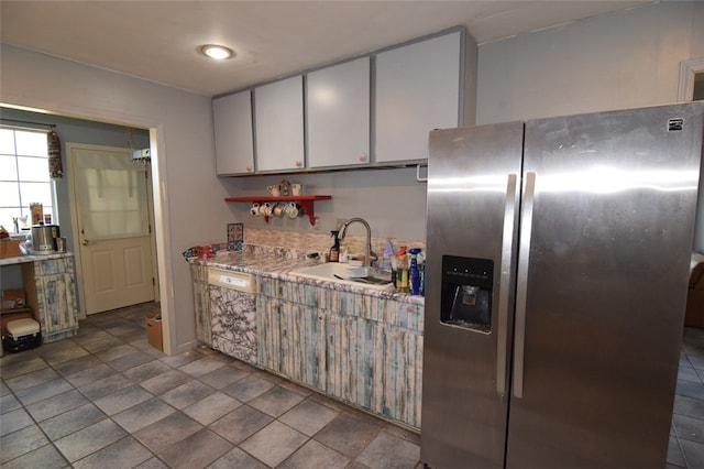kitchen with light countertops, a sink, and stainless steel fridge with ice dispenser