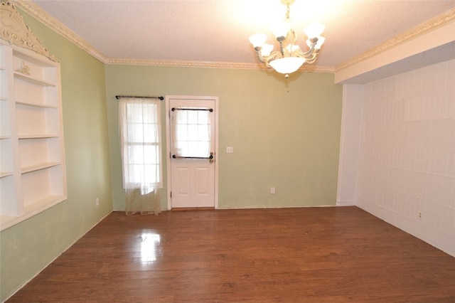 empty room with a notable chandelier, crown molding, a textured ceiling, and wood finished floors