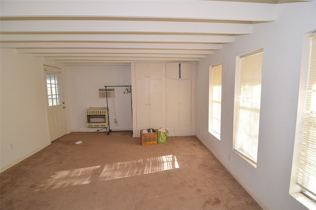 unfurnished bedroom with heating unit, beam ceiling, multiple windows, and light carpet